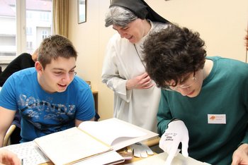 Teamwork: Archiv und Schule Teamwork: Archiv und Schule; zwei Schüler und Schwester Barbara betrachten alte Urkunden